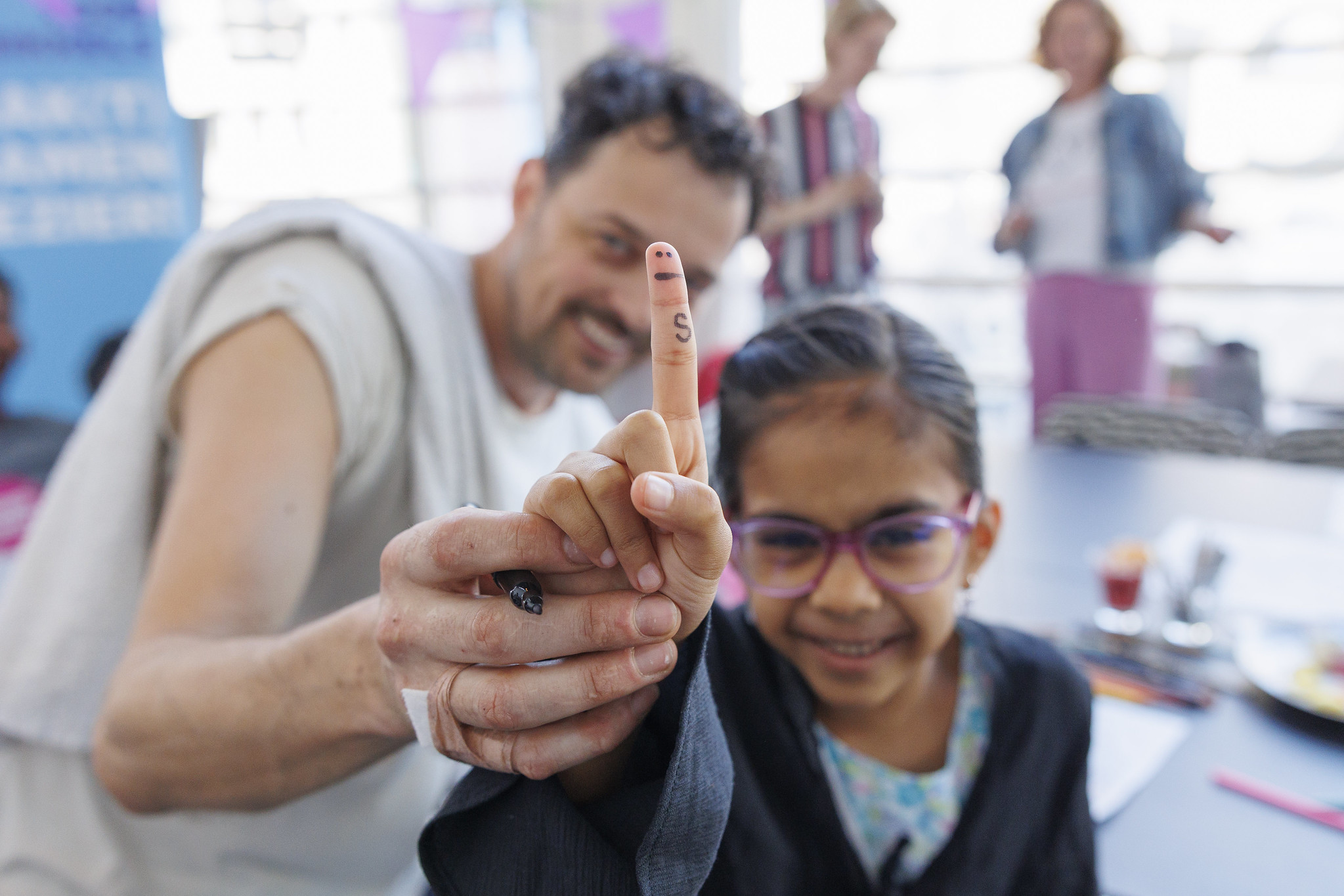 Meisje houdt haar vinger omhoog in de camera waar een gezichtje op is getekend: supervinger!