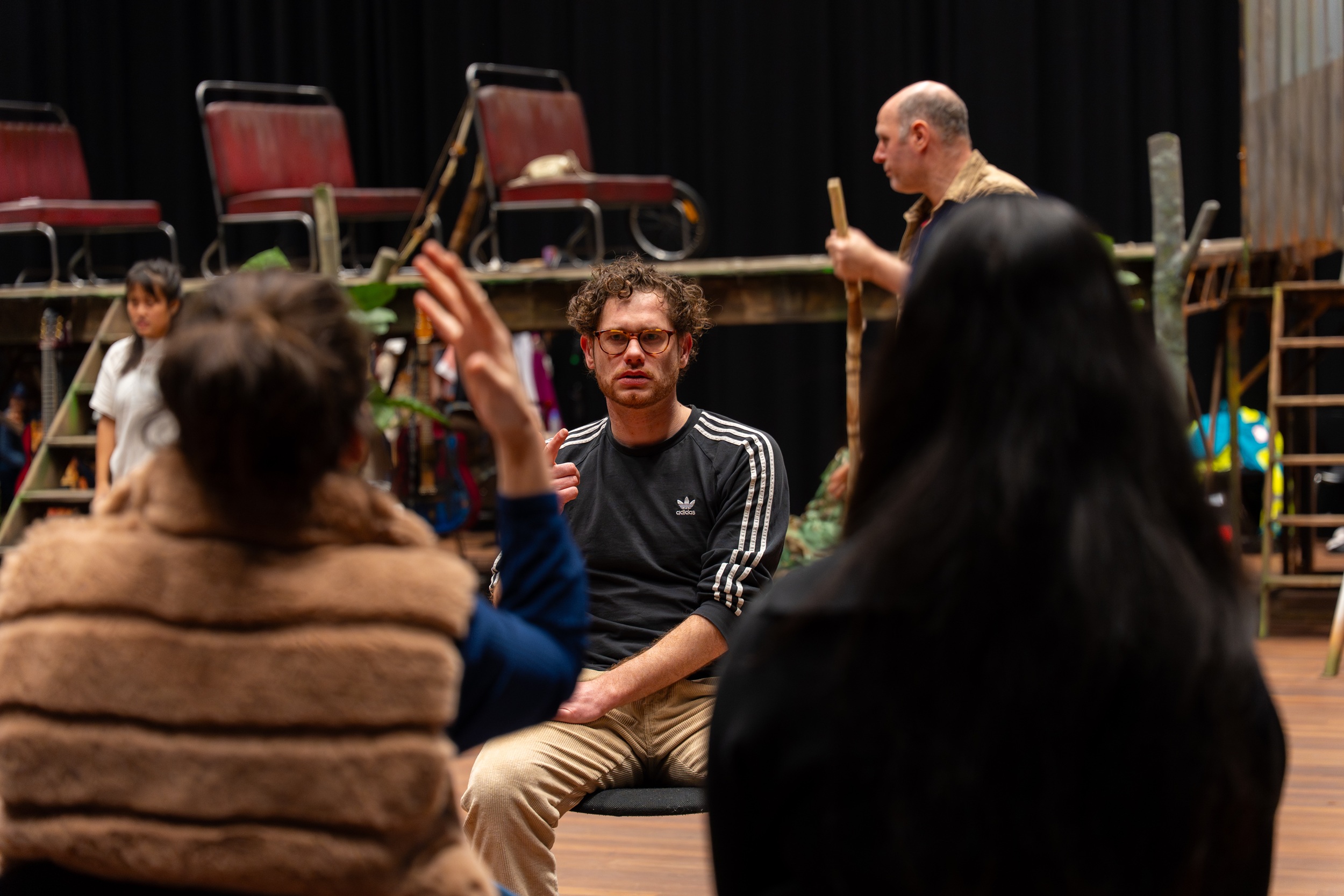 Tolken NGT gebaren naar Boaz wat de acteurs op de achtergrond zeggen.